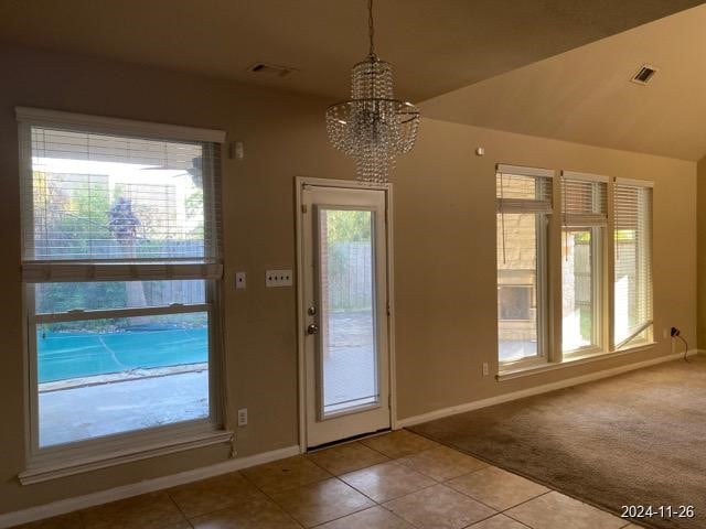 doorway to outside with a wealth of natural light, light tile patterned flooring, and a notable chandelier