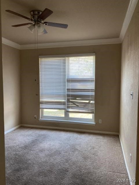 empty room with ceiling fan, plenty of natural light, carpet floors, and ornamental molding