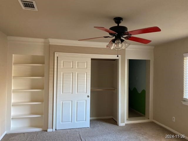 unfurnished bedroom featuring carpet, ceiling fan, and crown molding