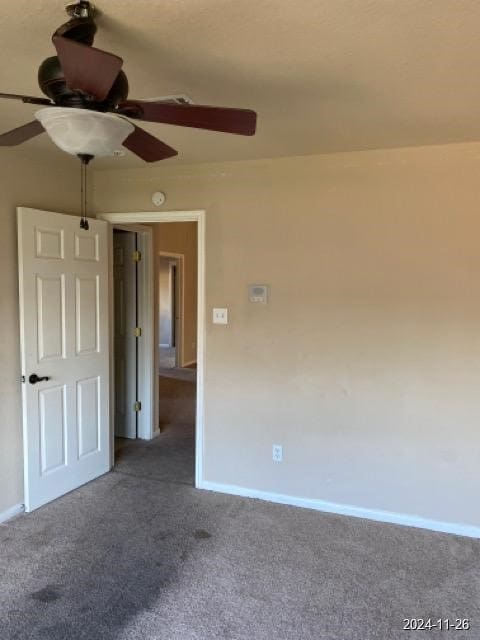 empty room featuring ceiling fan and dark carpet