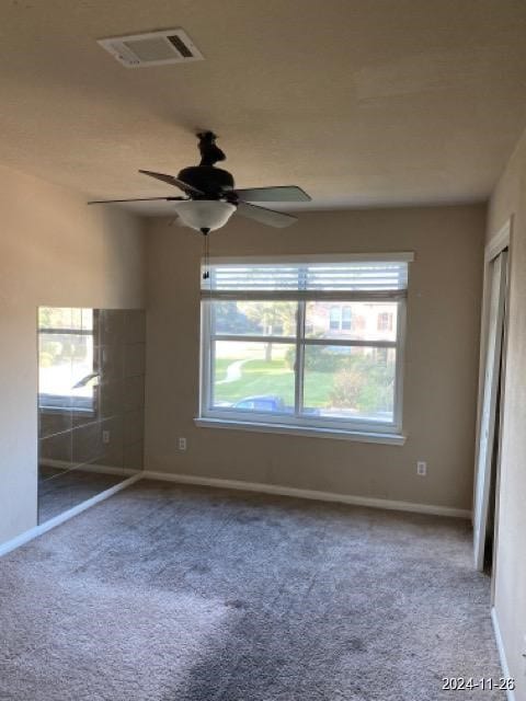 empty room featuring plenty of natural light, ceiling fan, and carpet floors