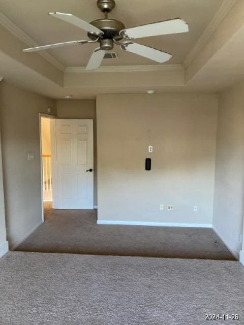 carpeted empty room with a tray ceiling, crown molding, and ceiling fan