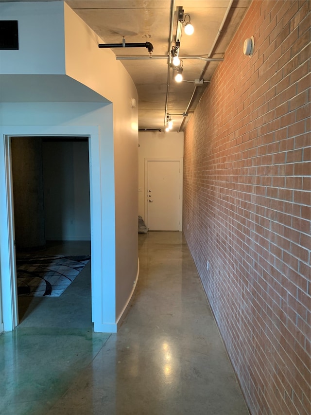 hallway with brick wall and concrete floors