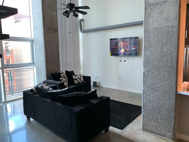 living room featuring concrete flooring, ceiling fan, and a healthy amount of sunlight