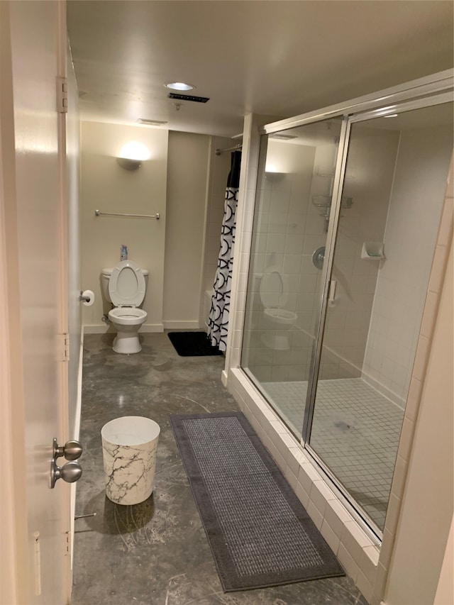 bathroom featuring a shower with shower door and toilet