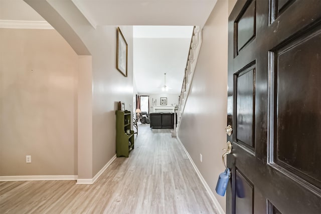 corridor with ornamental molding and light hardwood / wood-style flooring