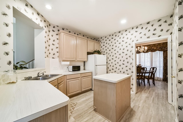 kitchen with white appliances, light brown cabinets, light wood-type flooring, and sink