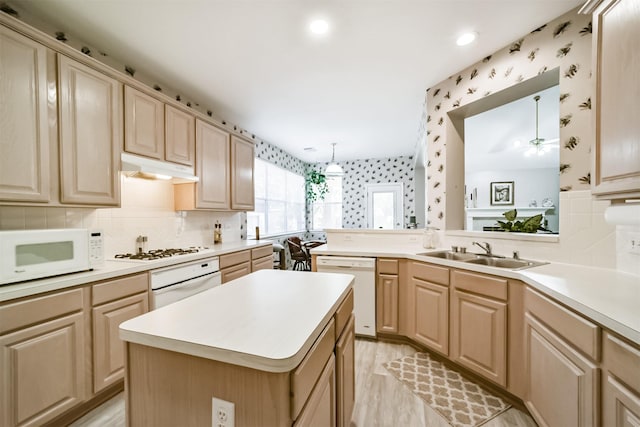 kitchen with sink, white appliances, light brown cabinetry, a kitchen island, and light wood-type flooring