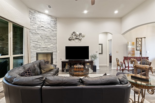 living room featuring ceiling fan, a fireplace, and light hardwood / wood-style floors