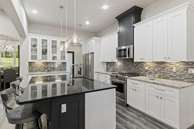 1617 Woodland Valley Dr, Huntsville, TX 77340 - kitchen featuring premium appliances, decorative light fixtures, a center island with sink, dark stone countertops, and white cabinetry