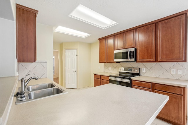 kitchen with backsplash, kitchen peninsula, sink, and stainless steel appliances