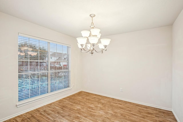 unfurnished room featuring hardwood / wood-style flooring and an inviting chandelier