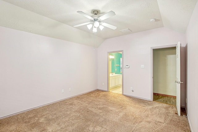 unfurnished bedroom with ceiling fan, a textured ceiling, connected bathroom, and vaulted ceiling