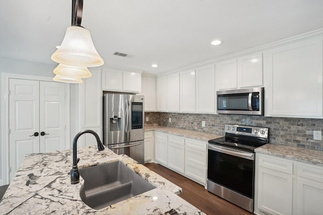 kitchen with pendant lighting, white cabinets, stainless steel appliances, and sink