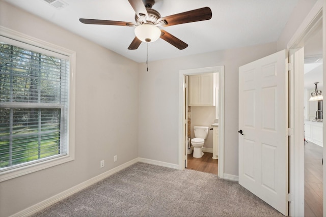 unfurnished bedroom with multiple windows, ceiling fan, carpet, and ensuite bathroom