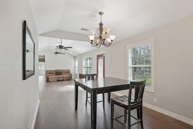 dining space with ceiling fan with notable chandelier, dark hardwood / wood-style flooring, vaulted ceiling, and a wealth of natural light