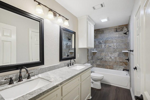 full bathroom with hardwood / wood-style flooring, vanity, toilet, and tiled shower / bath