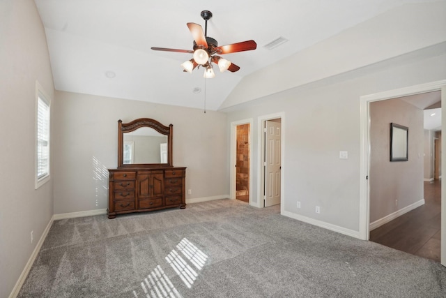 unfurnished bedroom featuring ceiling fan, carpet floors, connected bathroom, and vaulted ceiling