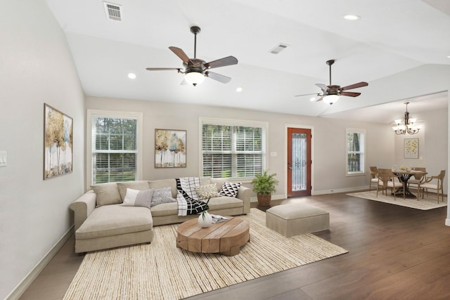 living room with ceiling fan with notable chandelier, a healthy amount of sunlight, dark hardwood / wood-style flooring, and lofted ceiling