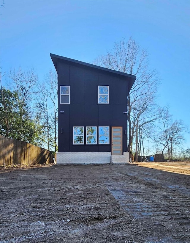 view of front of house featuring fence and brick siding