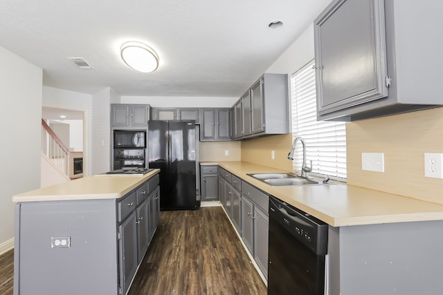 kitchen with gray cabinetry, dark wood-type flooring, black appliances, sink, and a kitchen island