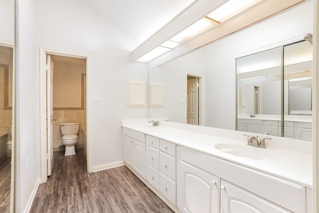 bathroom featuring lofted ceiling, toilet, vanity, tile walls, and hardwood / wood-style flooring