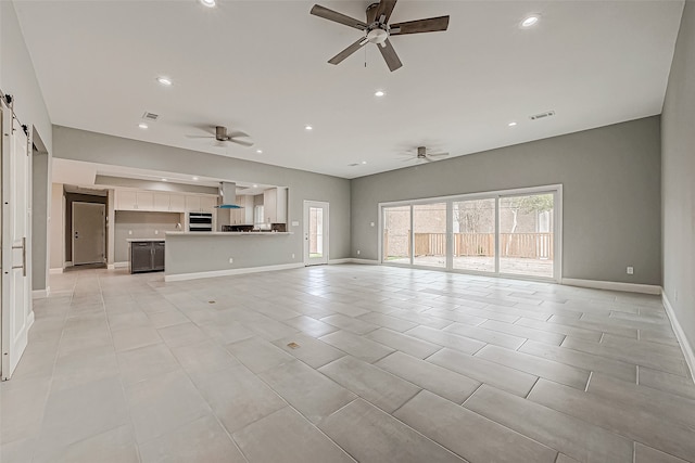 unfurnished living room featuring light tile patterned floors, a barn door, and ceiling fan