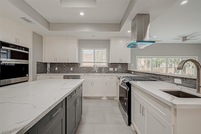 kitchen featuring island exhaust hood, a wealth of natural light, white cabinetry, and light stone countertops