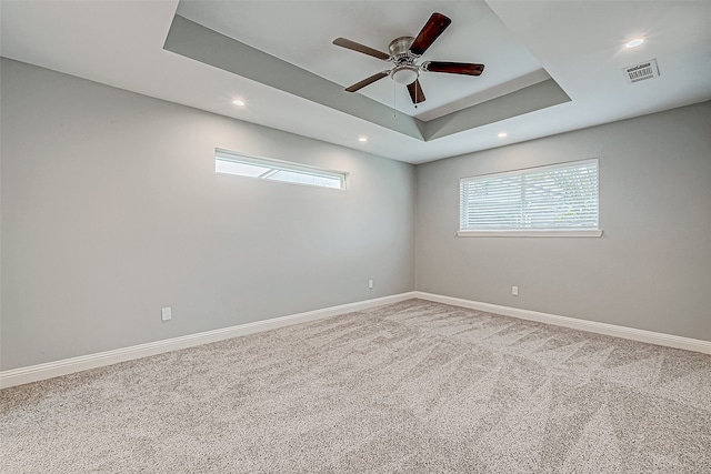 carpeted empty room featuring a raised ceiling and ceiling fan