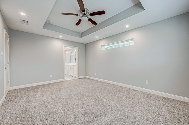 spare room with a raised ceiling, ceiling fan, and carpet