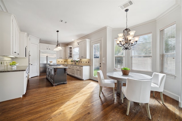 dining area with a notable chandelier, plenty of natural light, dark wood-type flooring, and sink