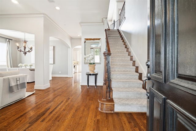 entryway with crown molding, dark hardwood / wood-style floors, and an inviting chandelier