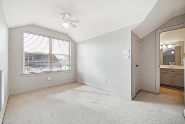 unfurnished bedroom featuring ceiling fan, light colored carpet, lofted ceiling, and ensuite bath