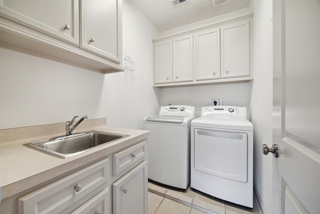 clothes washing area featuring cabinets, light tile patterned floors, sink, and washing machine and clothes dryer