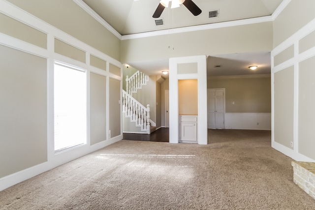 carpeted empty room featuring crown molding, ceiling fan, and a high ceiling