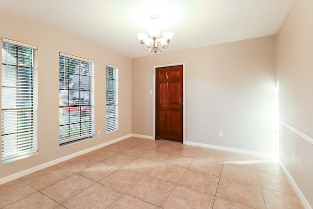 empty room with a chandelier and light tile patterned floors