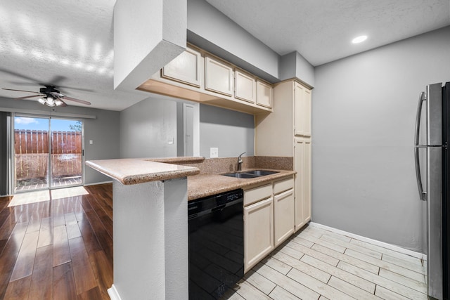 kitchen featuring sink, light hardwood / wood-style flooring, cream cabinetry, black dishwasher, and stainless steel refrigerator