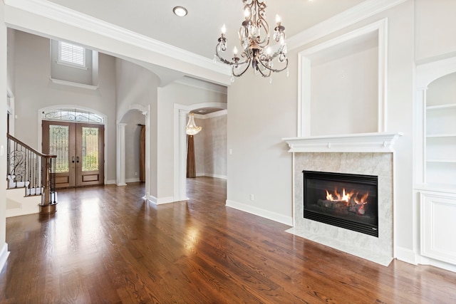 unfurnished living room featuring dark hardwood / wood-style flooring, crown molding, french doors, and a notable chandelier