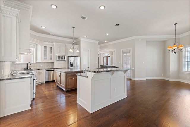 kitchen with a center island, dark stone counters, white cabinets, appliances with stainless steel finishes, and dark hardwood / wood-style flooring