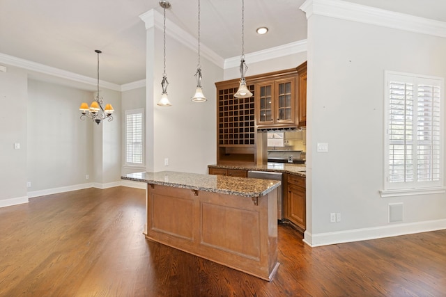 kitchen featuring dark hardwood / wood-style flooring, light stone counters, hanging light fixtures, and a healthy amount of sunlight