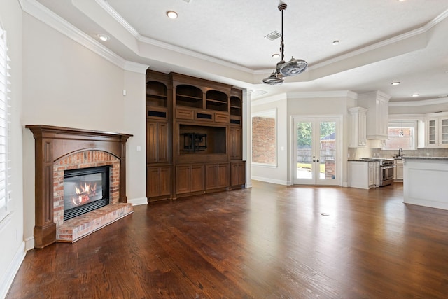 unfurnished living room featuring crown molding, dark wood-type flooring, and a tray ceiling