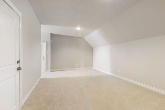 additional living space with light carpet and vaulted ceiling