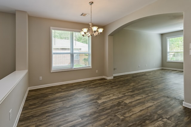 unfurnished room featuring dark hardwood / wood-style flooring, a wealth of natural light, and a chandelier