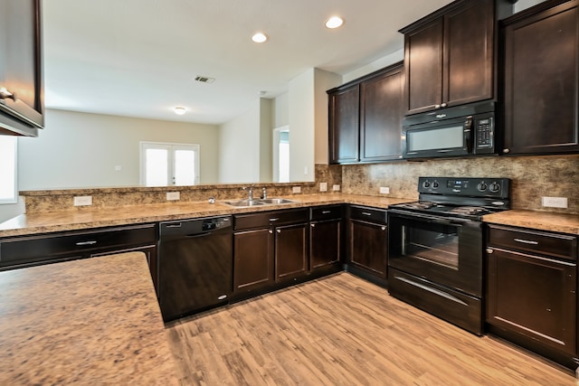 kitchen featuring backsplash, sink, black appliances, and light hardwood / wood-style flooring