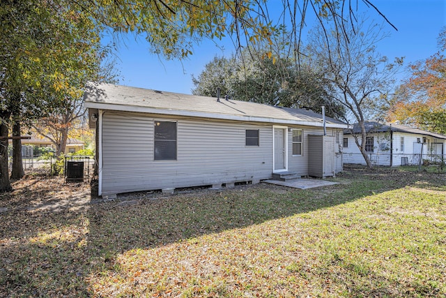 rear view of property with a lawn and central air condition unit