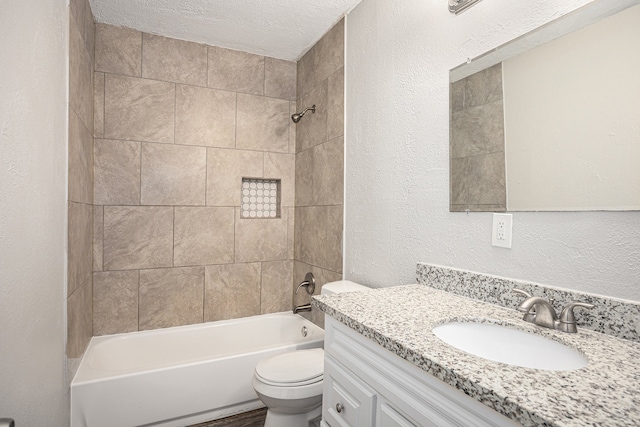 full bathroom with vanity, tiled shower / bath, a textured ceiling, and toilet