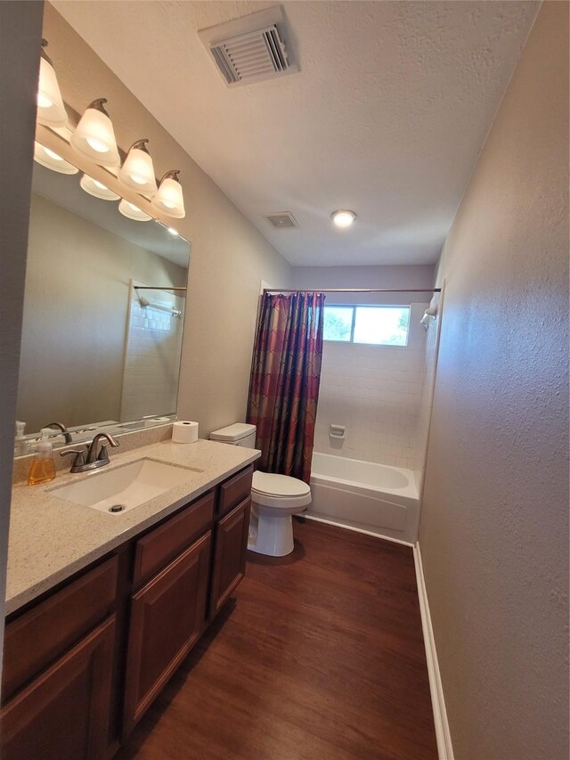 full bathroom with hardwood / wood-style floors, shower / bath combination with curtain, a textured ceiling, toilet, and vanity