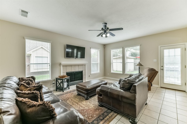 tiled living room with ceiling fan, a healthy amount of sunlight, and a tile fireplace