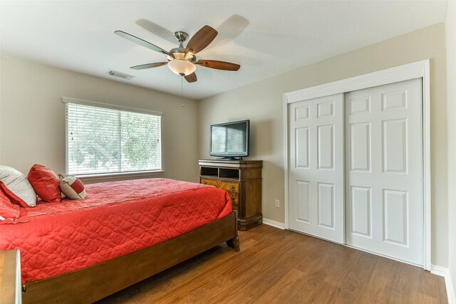 bedroom with ceiling fan, wood-type flooring, and a closet