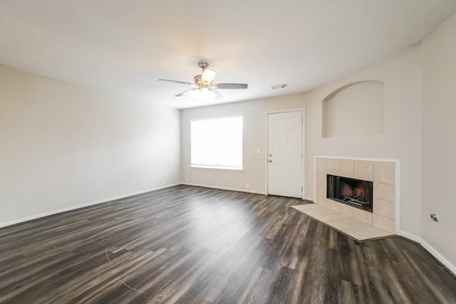 unfurnished living room with ceiling fan, dark hardwood / wood-style flooring, and a tile fireplace